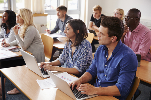 Students learning at desks with laptops